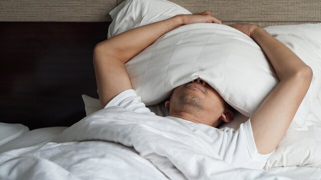 a man cover his face with a pillow. Got depression. Mental health concept