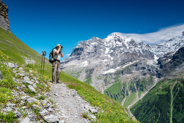 Fototapeta premium Switzerland travel - Senior man hiking and taking a photograph of the scenic Jungfrau region of the Swiss alps in Switzerland.