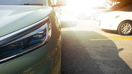 Fototapeta premium Close up of car soft green color headlight on parking lot. with blurred of other cars in parking lot under roof for background. And strong sunlight