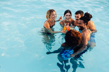 Friends toasting with drinks in swimming pool during summer vacation