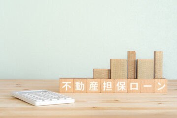 不動産担保ローンと書かれたブロック、不動産の模型、電卓