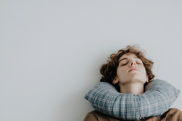 Relaxed Young Person with Neck Pillow Against Light Wall Background