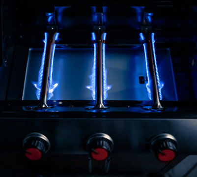 blue fire of a gas grill tube burners, closeup view