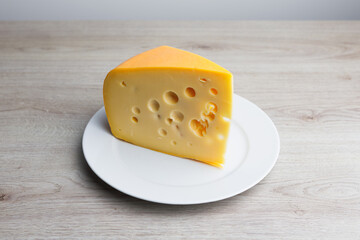 maasdam cheese on a plate, grey background
