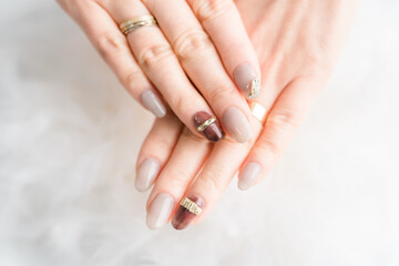 ネイルサロン・ジェルネイルをする女性（ベージュ・ブラウン・秋冬デザイン）
