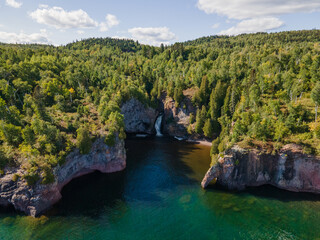 A stunning aerial view of Manitou River waterfall cascading into Lake Superior along Minnesota’s...