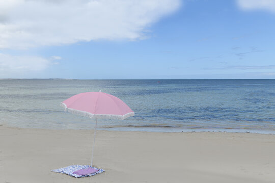 Pink beach umbrella on the coastline