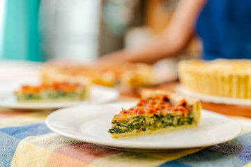 Chef serving slice of delicious spinach and bacon quiche