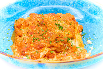 Traditional italian dish lasagna alla bolognese in the blue plate with white background