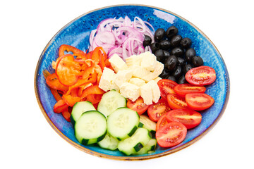 Greek salad with Cherry tomatoes, cucumber, peppers, olives, Greek feta cheese, red onions in the blue plate with white background