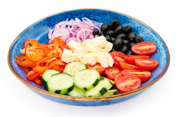 Greek salad with Cherry tomatoes, cucumber, peppers, olives, Greek feta cheese, red onions in the blue plate with white background