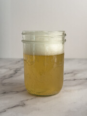 Glass of kombucha in a mason jar glass, small amount of foam