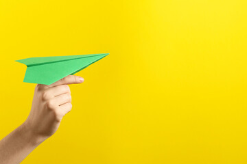 Woman with green paper plane on yellow background, closeup. Space for text