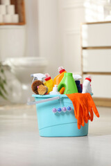 Bucket with different cleaning supplies on floor in bathroom