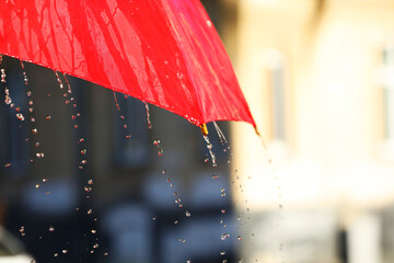 Open red umbrella under pouring rain outdoors, closeup. Space for text
