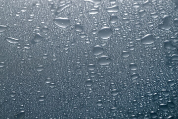 Water drops on grey glass surface, top view