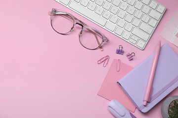 Designer's workplace with keyboard and stationery on pink background, flat lay. Space for text