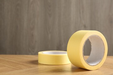 Two masking tapes on wooden table, closeup. Space for text