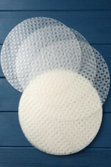 Edible rice paper sheets on blue wooden table, flat lay