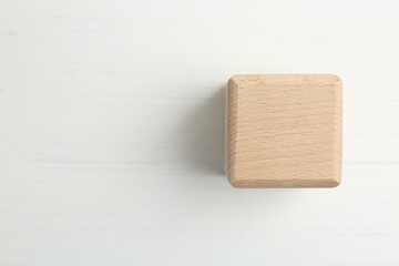 One wooden cube on white table, top view. Space for text