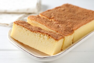 Tasty Japanese Castella sponge cake on white wooden table, closeup