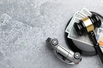 Motor vehicle accident law. Gavel, money and car model on grey background, top view. Space for text