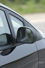 Closeup of Black Car Side Mirror Reflecting Road