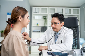 Asian cardiologist doctor listen to heartbeat patient woman in hospital.	
