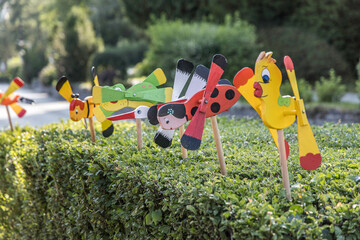 Colorful windmills on hedge, toy windmill, natural wind, natural energy, artificial wind turbines,blurred background, close up.