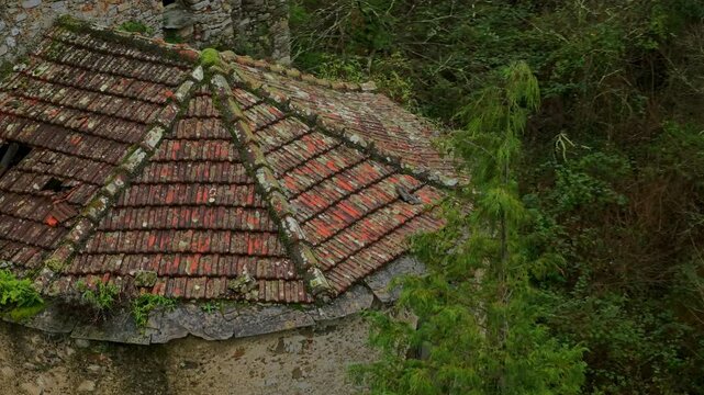 Ghostly abandoned church, Santa Maria di Lago Pigo, Nostra Signora di Nogareto or Madonna dell&rsquo;Assunta with gray stone, red tile roof, dense vegetation, and wooded hills. Aerial drone view, close-up