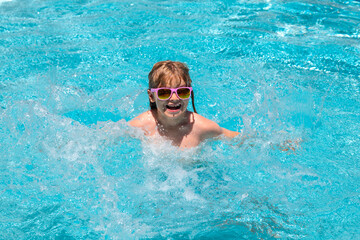 Children playing in the swimming pool. Summer kids vacation, boy swim in pool. Summer activity.