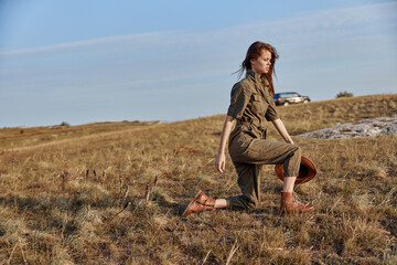 Woman kneeling in field with hat and boot beauty of nature and fashion in the outdoors