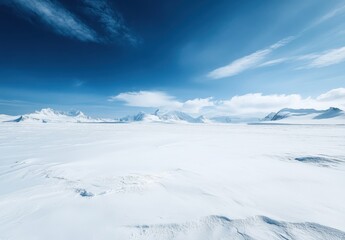 Fototapeta premium Expansive Snow-Covered Landscape Under Bright Blue Sky with Clouds and Majestic Mountains in the Background, Evoking Serenity and Isolation in Nature