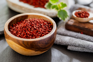 annatto grains in a container on a gray slate