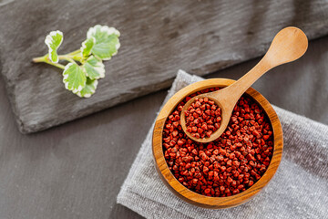 annatto grains in a container on a gray slate