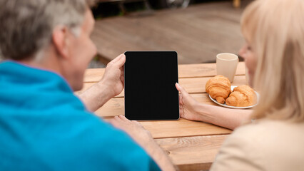 Mature married couple communicating with their son via tablet computer in countryside