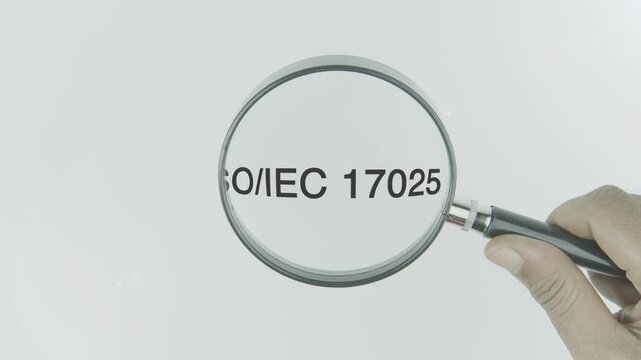ISO IEC 17025 text highlighted by a magnifying glass in a hand on a white background, symbolizing focus on laboratory standards, accreditation, and testing