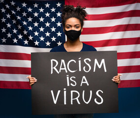 Racism is a virus. African american woman holding strike placard, american flag background