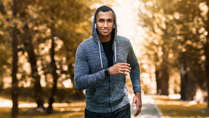 Obraz premium Smiling black athlete training for marathon at green park in summer, panorama