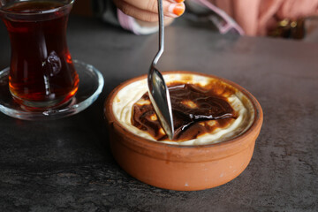 Creamy dessert topped with rich syrup beside a glass of tea