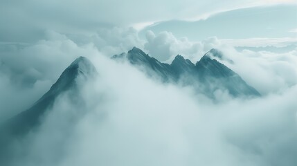 A misty mountain range shrouded in dense, swirling clouds, with the peaks barely visible through the fog.