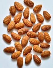 Fototapeta premium A collection of fresh, natural almonds is carefully arranged on a clean, white background. The almonds have a rich, warm brown color with a slightly rough, textured surface,.