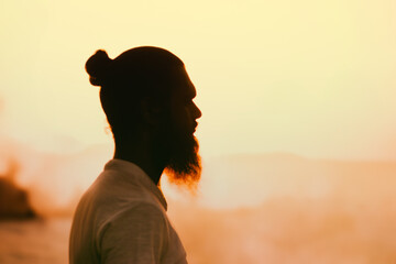 Silhouette of a man with long hair and beard against the sunset.