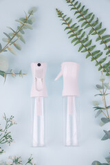 Minimalist Spray Bottles with Greenery on Pastel Blue Background