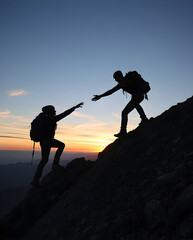 Hikers helping each other climb a mountain at sunset in silhouette.