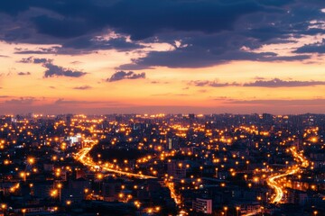 Fototapeta premium City lights illuminate the landscape during a vibrant sunset, creating a breathtaking panorama