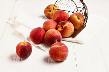 Basket with sweet peaches on white wooden background