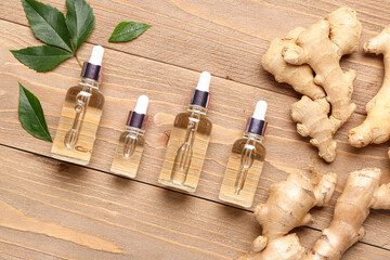 Bottles of ginger cosmetic oil and leaves on wooden background