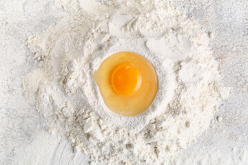 Heap of flour with raw chicken egg for preparing bakery on grunge background