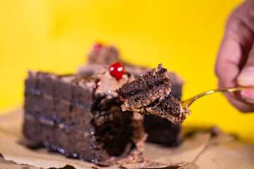 Hand taking a small portion of chocolate cake from slice